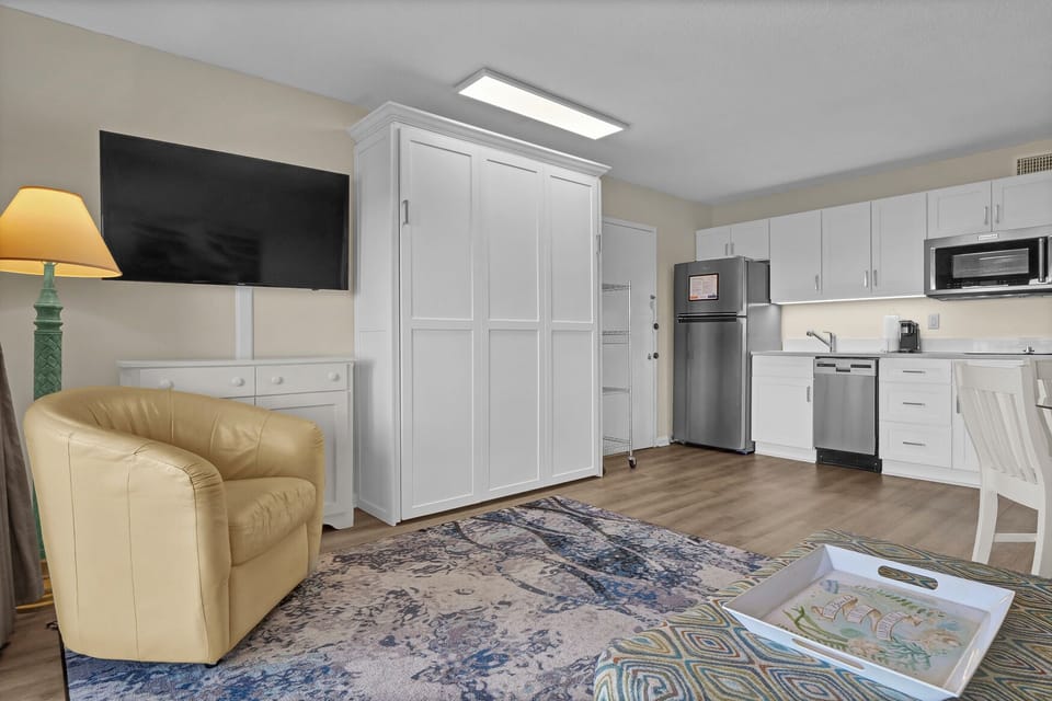 Relax in your bright studio with a cozy leather armchair, full kitchen, and clever Murphy bed for flexible living.