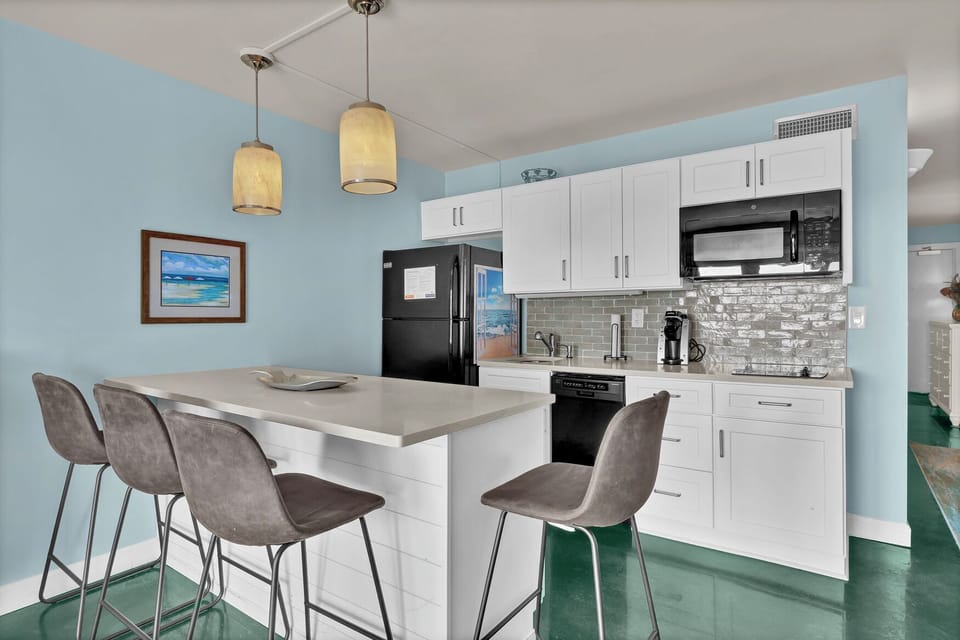 Whip up your favorite meals in this bright, modern kitchen featuring sleek white cabinets, stylish pendant lighting, and a convenient breakfast bar.