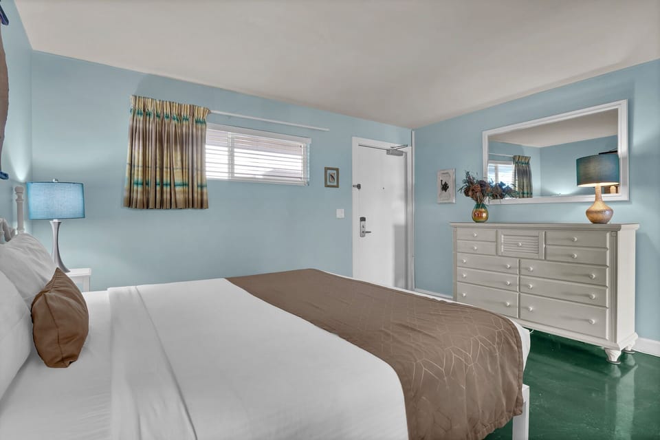 Relax in your peaceful bedroom with soothing blue walls, comfortable bedding, and thoughtful touches like reading lamps and ample dresser storage.