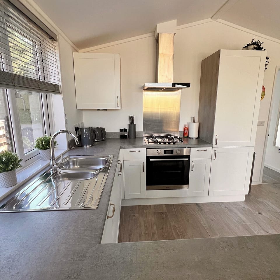 The modern kitchen is fully equipped with essential appliances, including a microwave, fridge-freezer, dishwasher, and washing machine. All necessary cooking utensils are provided. 