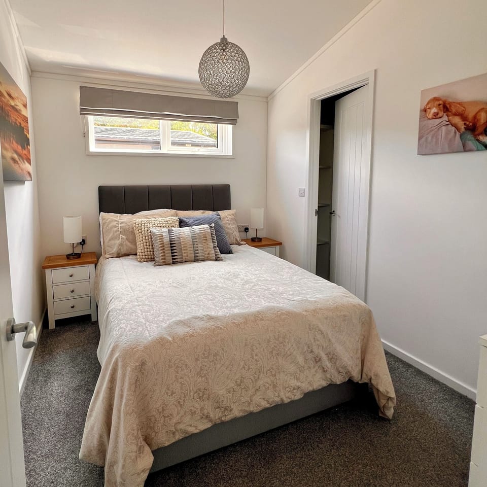 The double bedroom features a tranquil atmosphere with bedside tables and lamps on either side of the bed. A spacious walk-in wardrobe offers ample shelving and hanging space for convenient storage. 