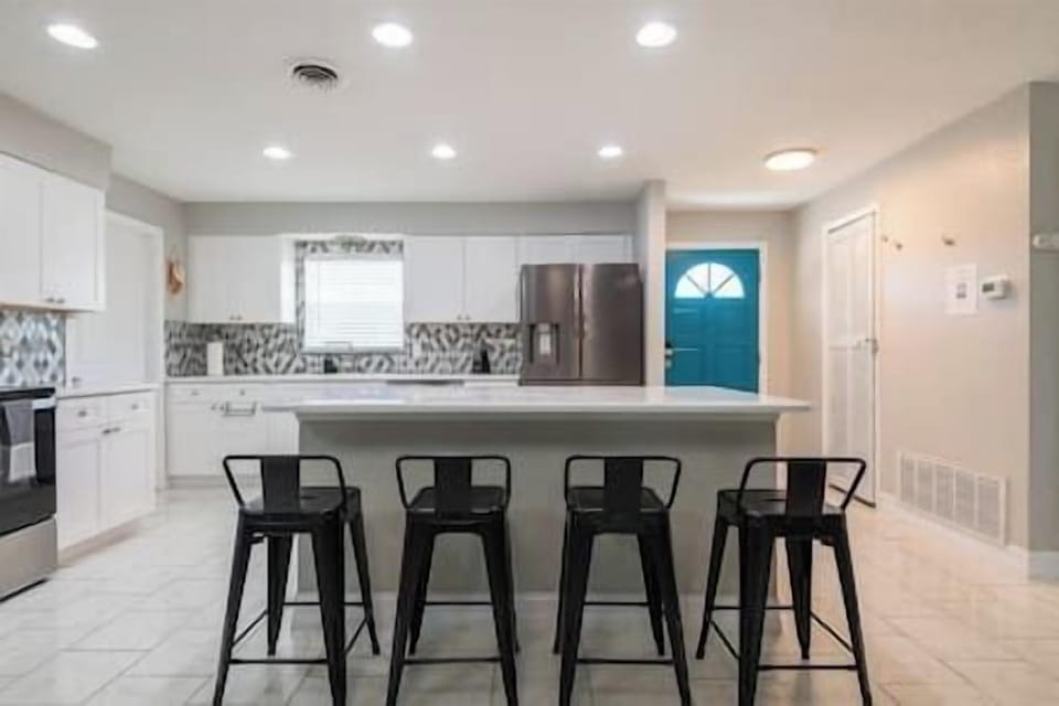 Step into a fully equipped kitchen w/stainless steel appliances & custom countertop w/bar stools