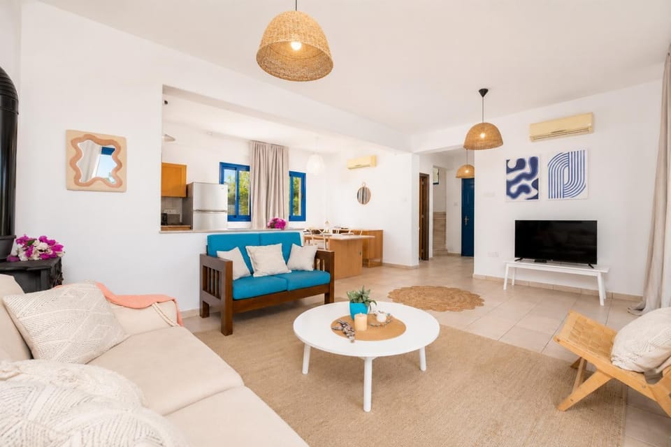 Open-plan living room with sofa, dining area, kitchen, A/C, WiFi internet, and satellite TV
