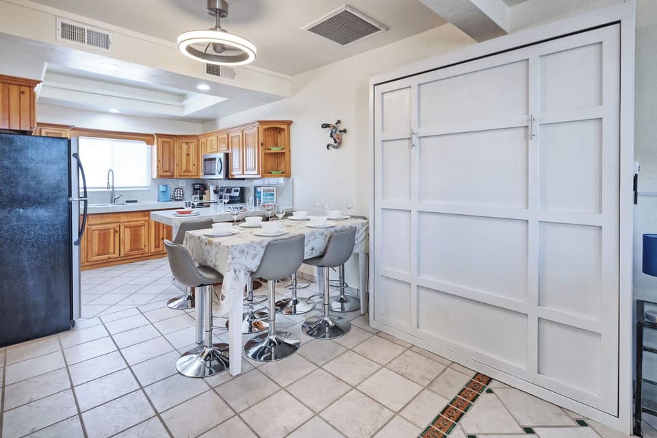 Spacious kitchen and dining area featuring a full-size Murphy bed, breakfast bar seating, and plenty of natural light—perfect for gathering or extra sleeping space.