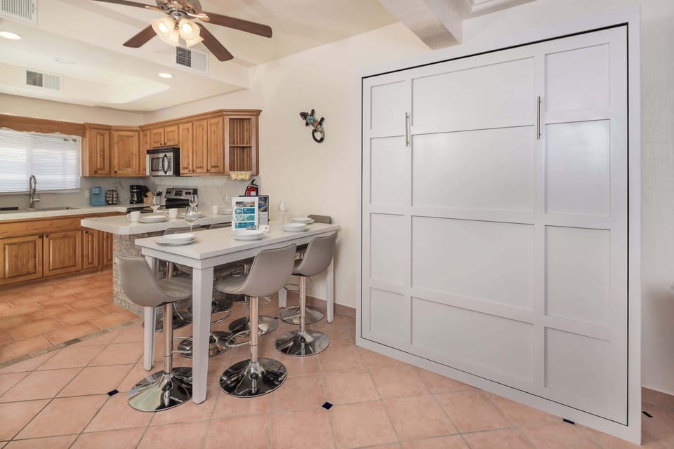 Spacious kitchen and dining area featuring a full-size Murphy bed, breakfast bar seating, and plenty of natural light perfect for gathering or extra sleeping space.