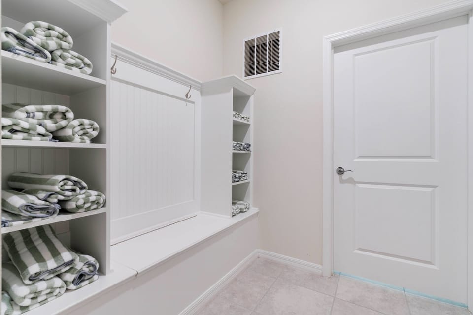 Step into a beautifully organized space with soft, neatly folded towels on elegant shelves. The clean white cabinetry and bright ambiance create a refreshing atmosphere, ensuring your stay is both comfortable and convenient.
