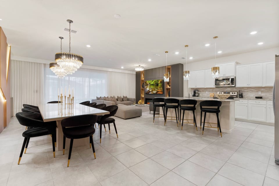 Enjoy the spacious open-concept dining and living area, highlighted by a stylish table and plush black chairs under elegant pendant lighting. The soft colors and modern touches make it an inviting space for your gatherings.