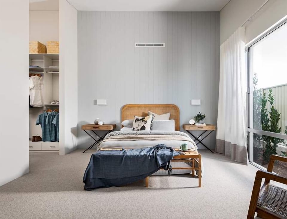 Wake up refreshed in the spacious primary bedroom, featuring a king bed, soft neutral tones, a walk-in wardrobe and natural light streaming through the glass doors.
