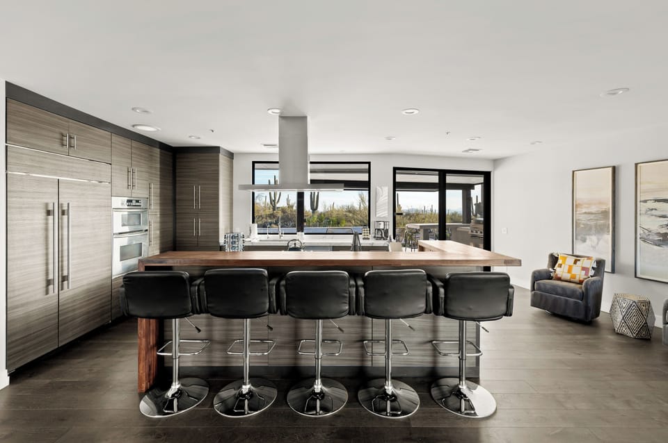 Fully stocked kitchen with barstool seating on a custom wood bar top, marble waterfall island, and stainless steel appliances