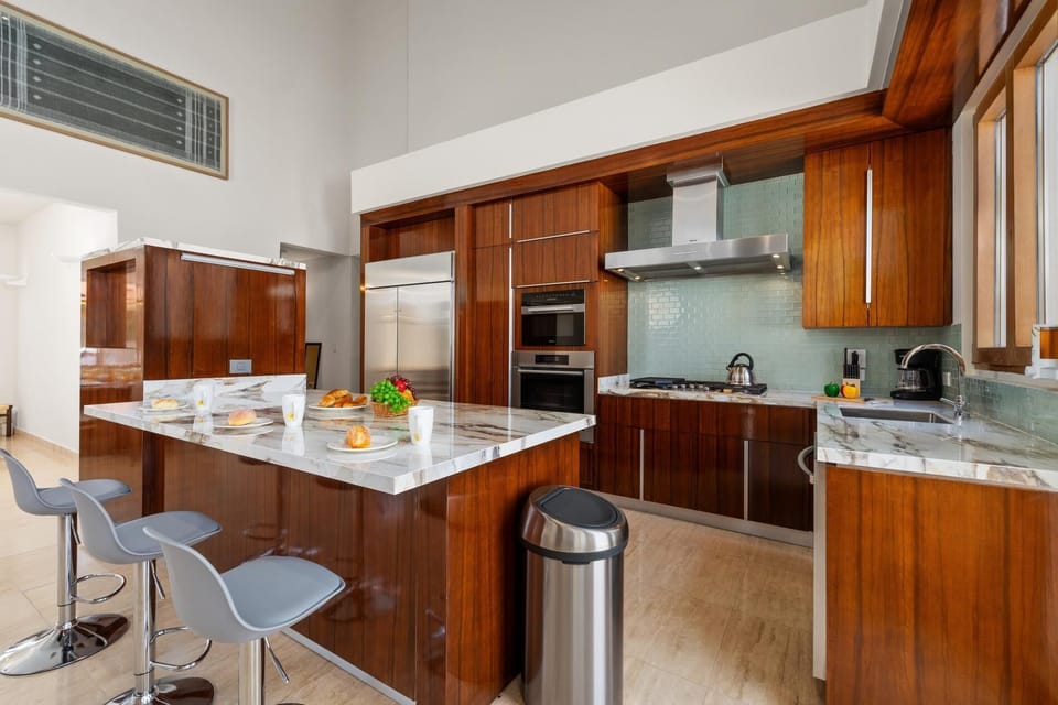 This sleek kitchen boasts a stunning array of stainless steel appliances,  expansive countertops, providing ample space for culinary creativity and effortless meal preparation, making it the perfect hub for any discerning chef.