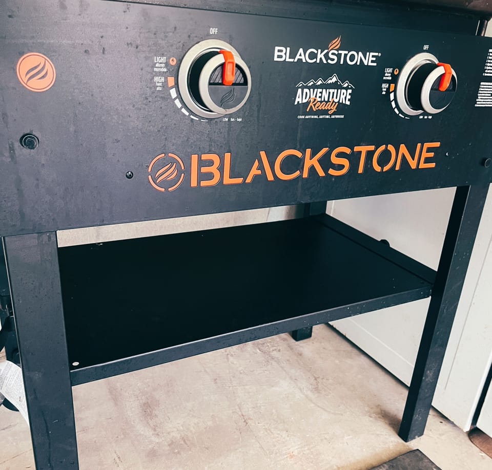 Black stone grill equipped with propane tank for use 