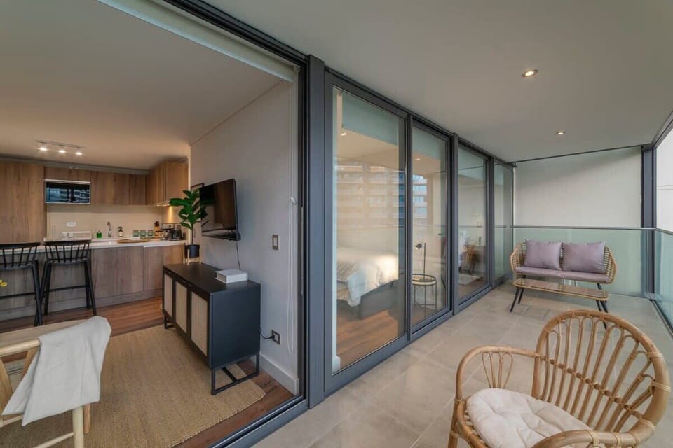 Relax on the stylish glass-enclosed patio with cozy wicker seating, perfect for unwinding after exploring the vibrant city of Chile.