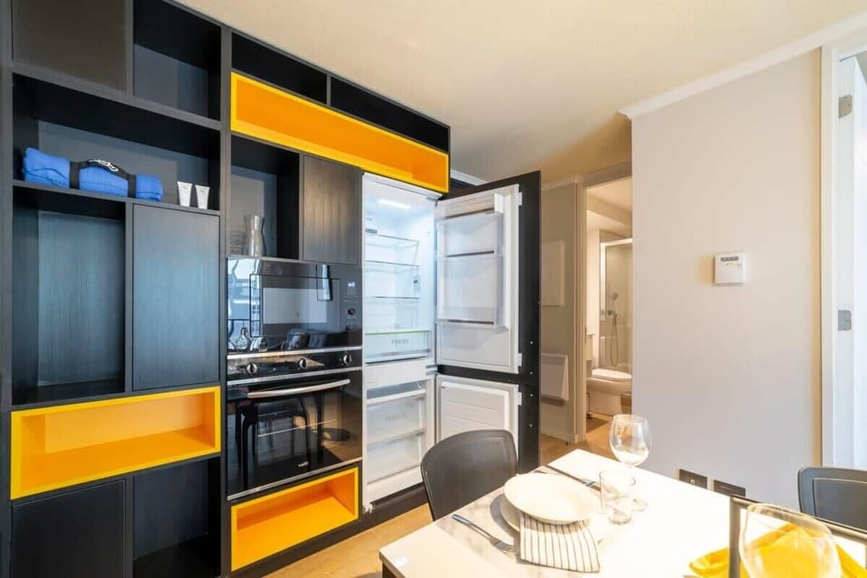 Sleek and modern kitchen with vibrant accents, perfect for cozy meals in your stylish studio retreat.