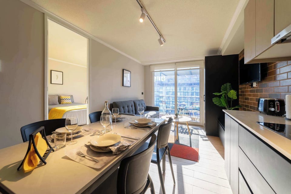 Bright and modern living space with a cozy sofa and dining area, leading to a sunlit balcony perfect for relaxation.