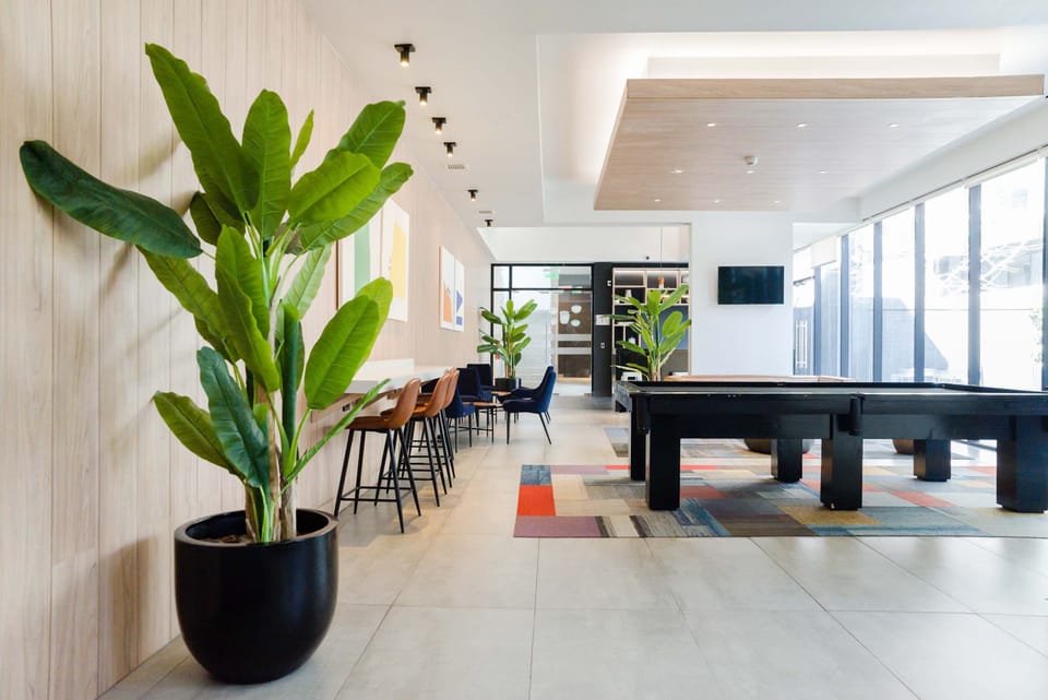 Enjoy a game of pool in this stylish and spacious common area with modern decor and ample natural light.