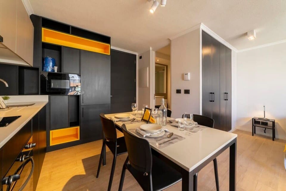 Modern dining space with sleek kitchen and vibrant accents, perfect for cozy meals.