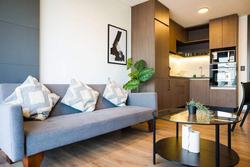 Stylish living area with modern kitchen, cozy sofa, and chic decor—perfect for relaxation and culinary adventures.