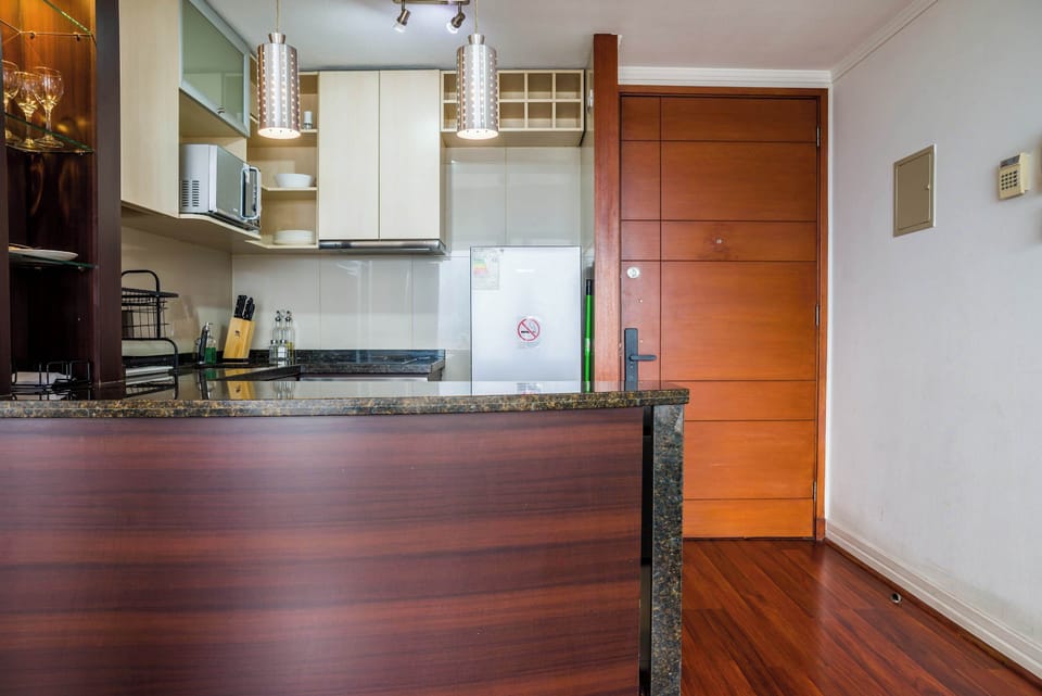 Compact studio kitchen with polished granite breakfast bar, pendant lighting, organized cabinetry, and essential cookware for easy in-home meals.
