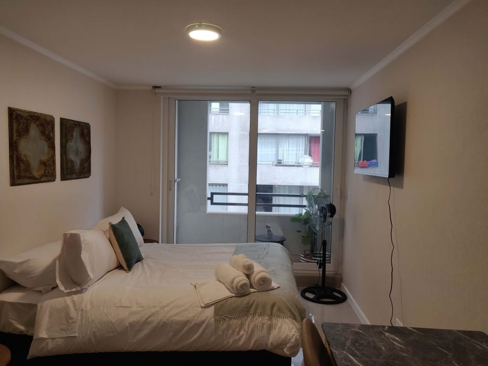 Cozy studio with a comfortable bed, balcony access, and modern amenities for a relaxing stay.