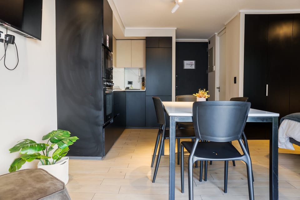 Stylish kitchen with sleek black cabinets and dining area, ideal for cozy meals in a modern setting.