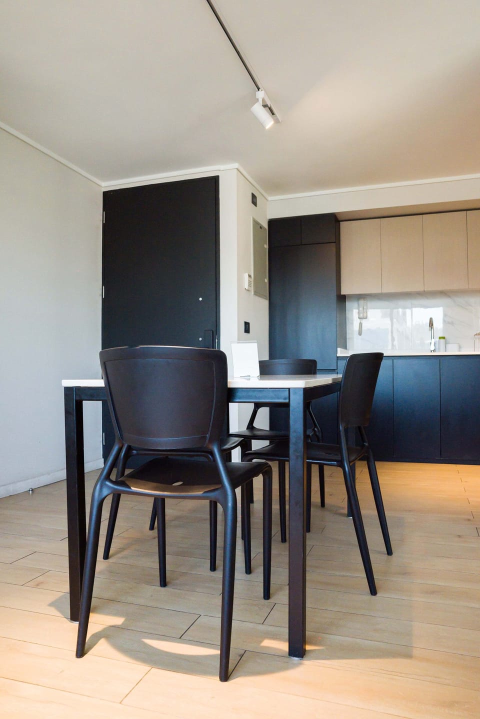 Sleek dining area with modern black furniture and a stylish kitchen backdrop, ideal for intimate meals.