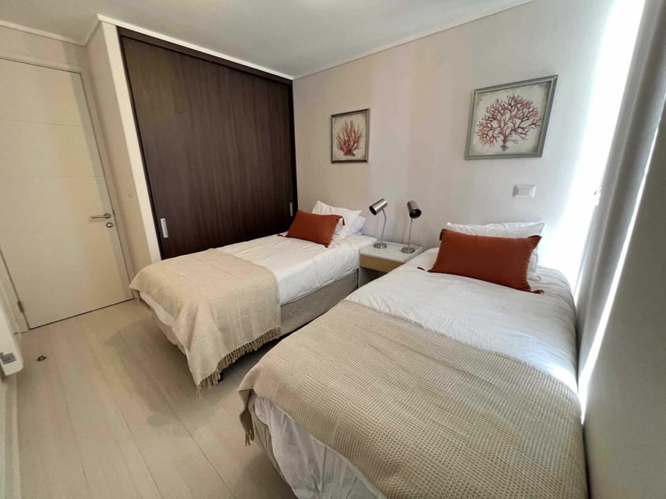 Cozy secondary bedroom with twin beds, ideal for children or friends, featuring warm decor and natural light.