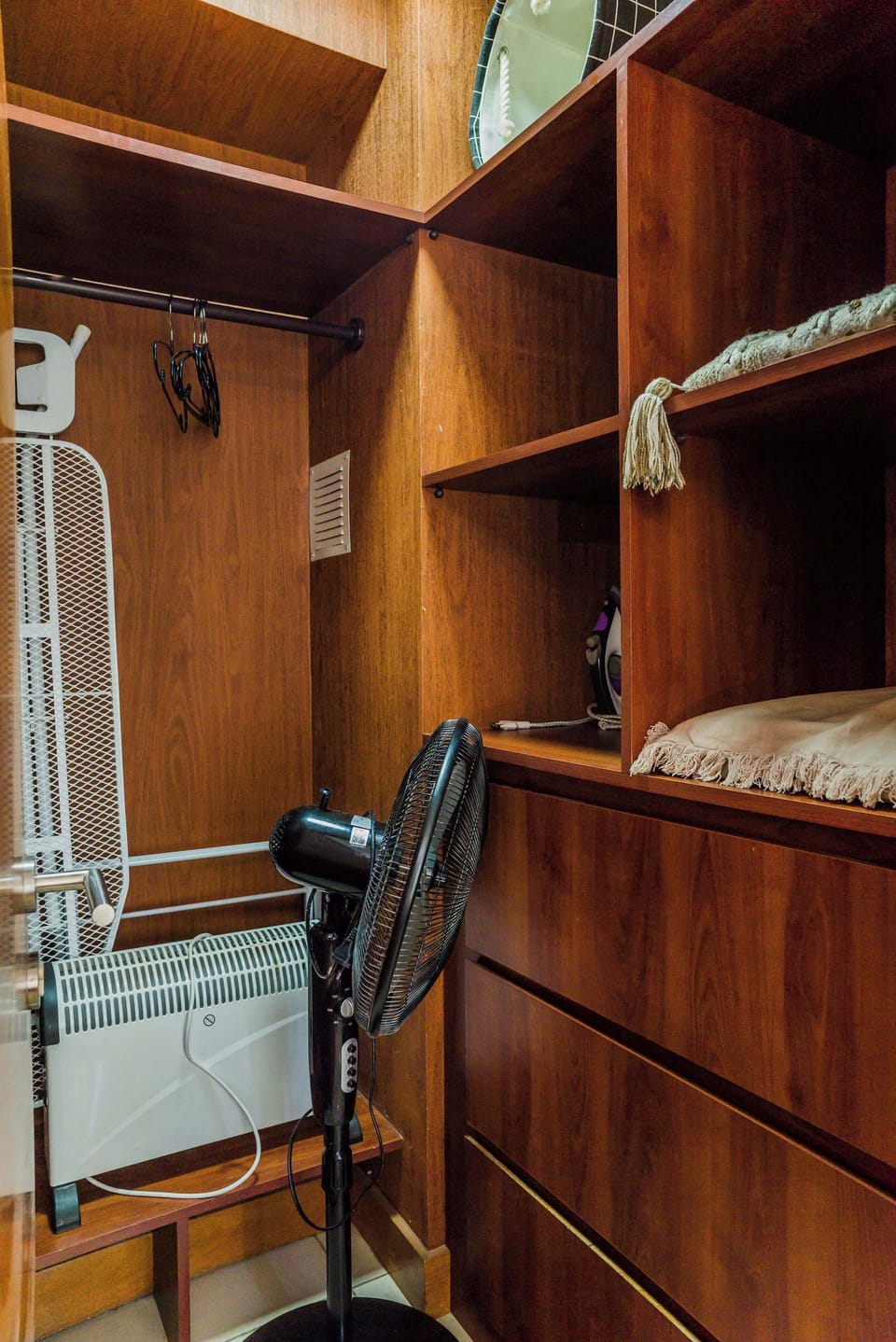 Organized storage space with essential amenities like an ironing board and heater for your convenience.