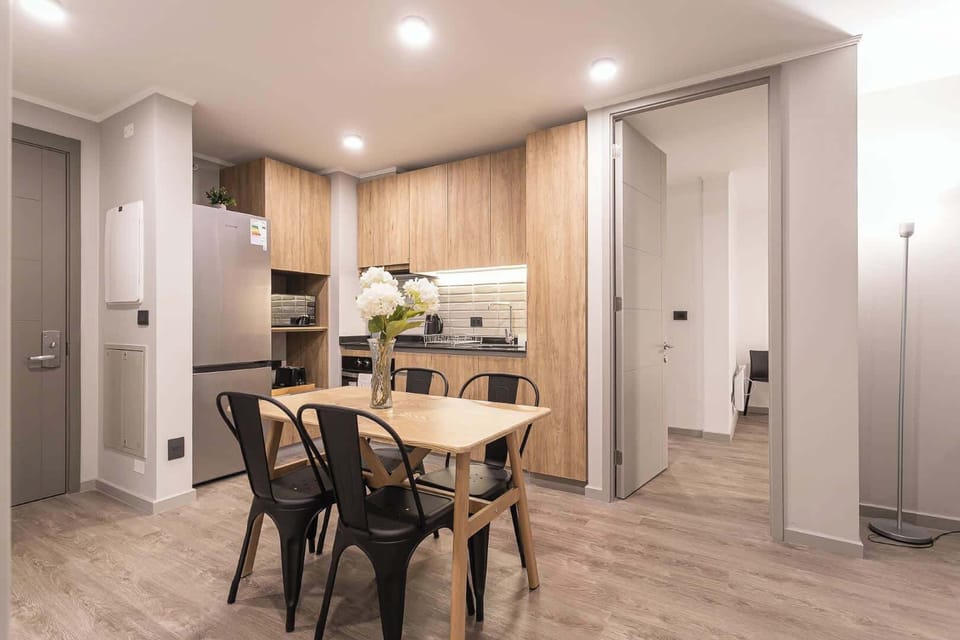 Modern kitchen with sleek wooden cabinets and a cozy dining area, perfect for enjoying meals with family or friends.