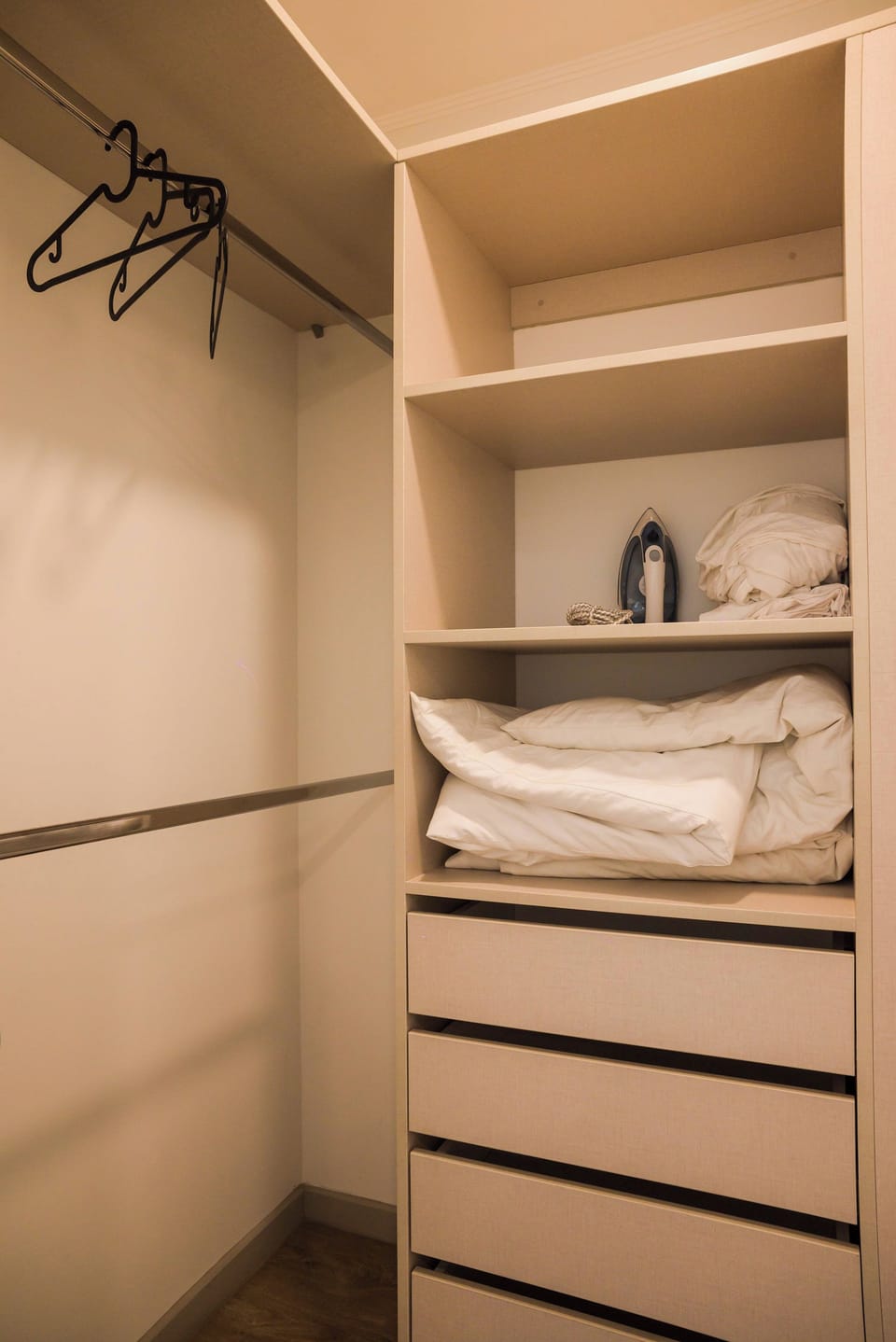 Bedroom storage with built-in light-wood drawers, shelving, and space for hanging clothes.