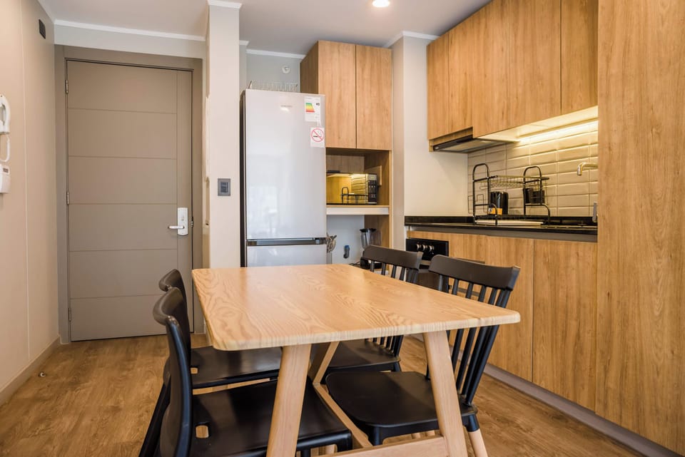 Private kitchen with warm wood cabinetry, a full-size refrigerator, and a dining table seating five.
