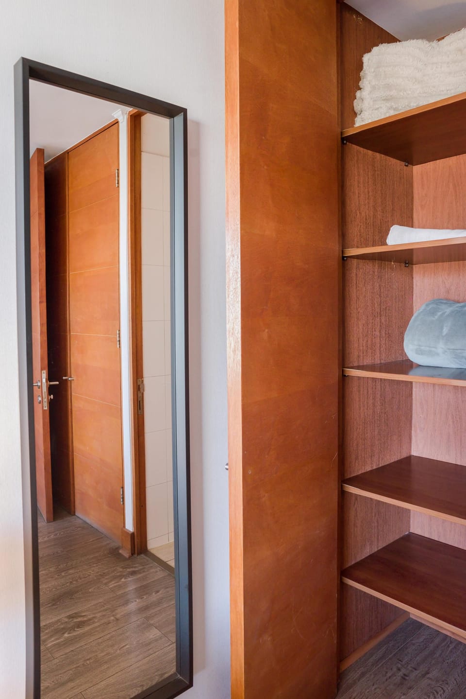 Spacious closet with ample shelving and a full-length mirror for a comfortable stay.