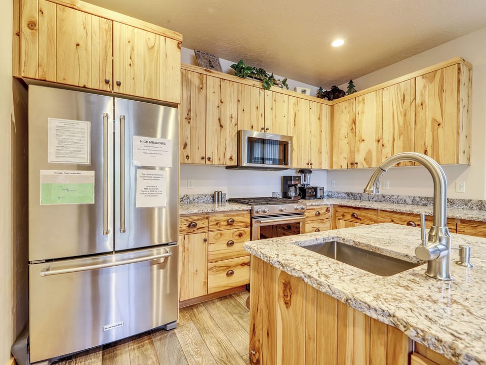 Kitchen equipped with KitchenAid appliances, including an oven, stove, microwave, and refrigerator/freezer. Features a stainless steel sink, upgraded cabinetry, and granite countertops for a modern, functional space.