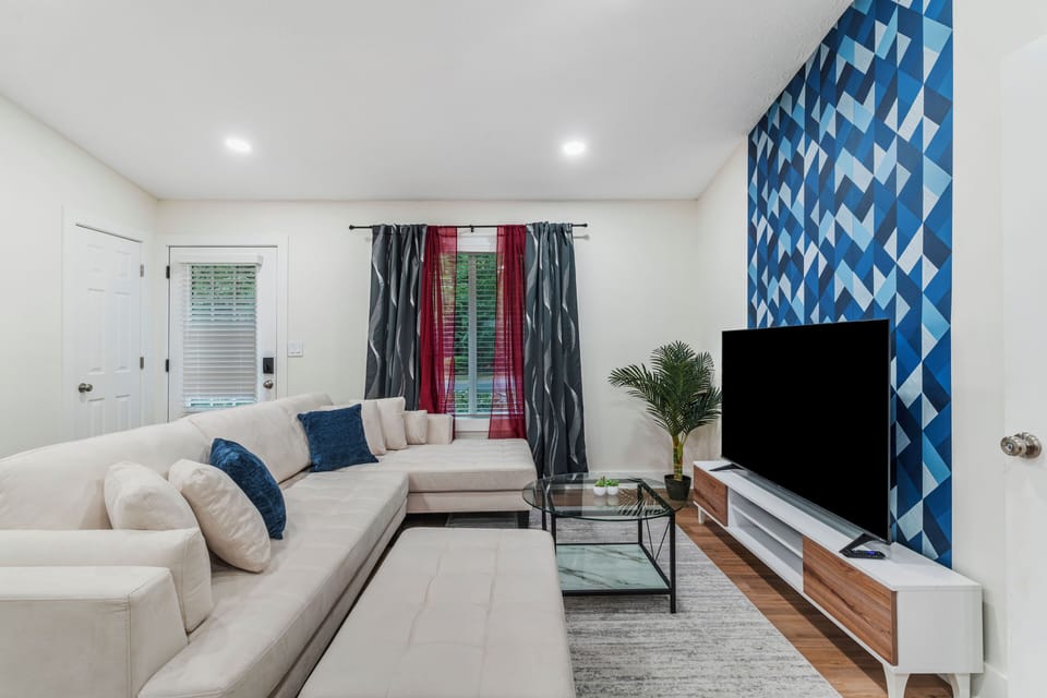 Cozy living room with white couch, TV and windows with curtains