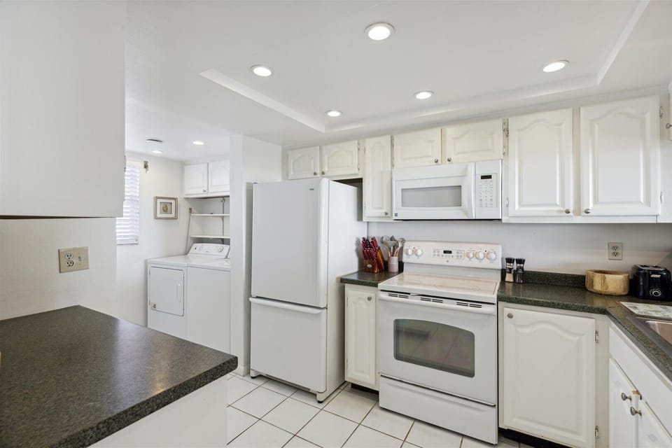 Bright and white kitchen area with appliances and ample cabinetry
