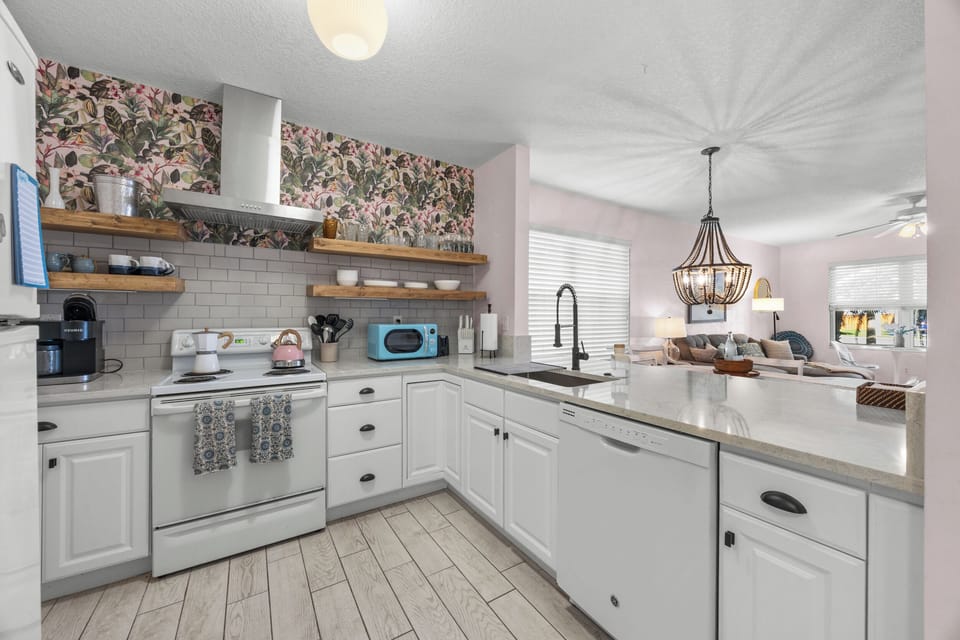 Open‑concept updated kitchen and living space with floating shelves and a bright coastal vibe.


