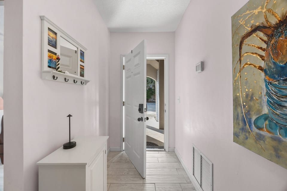 Bright and stylish entry hallway featuring coastal artwork, functional storage, and warm natural light.