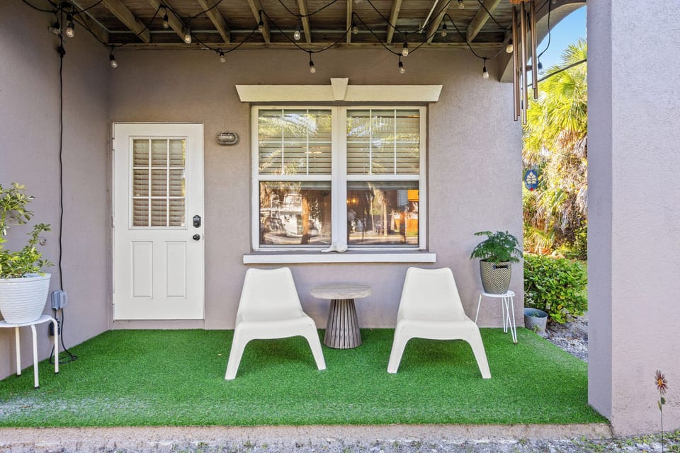 Cozy covered patio with string lights, modern seating, and lush greenery — the perfect spot to unwind.