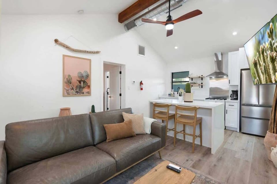 Open-plan hangout made for easy together time—stretch out on the sofa while snacks and drinks come together at the kitchen bar with stools and bright overhead lighting.