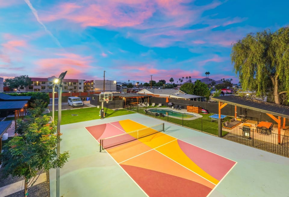 Colorful outdoor sport court under glowing sunset skies—lace up for a quick game, then linger as the lights come on and the evening cools down.