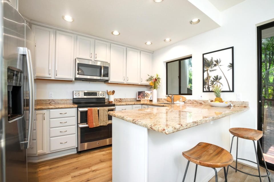  Cook and connect in a bright, refined kitchen with custom cabinetry, elegant finishes, and bar seating for two  