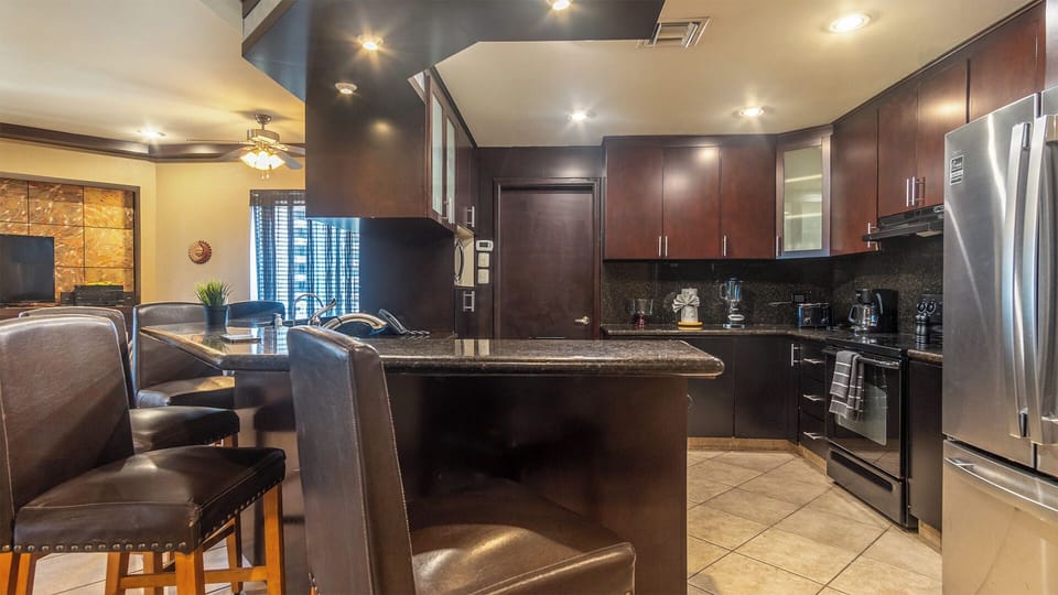 Dramatic with its dark granite and cabinets, the kitchen provides a spacious place to prepare meals.