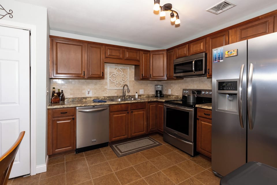 Well-equipped kitchen features modern stainless steel appliances, including a fridge with a water and ice dispenser, a dishwasher, and a microwave while the warm wood cabinets provide plenty of storage.