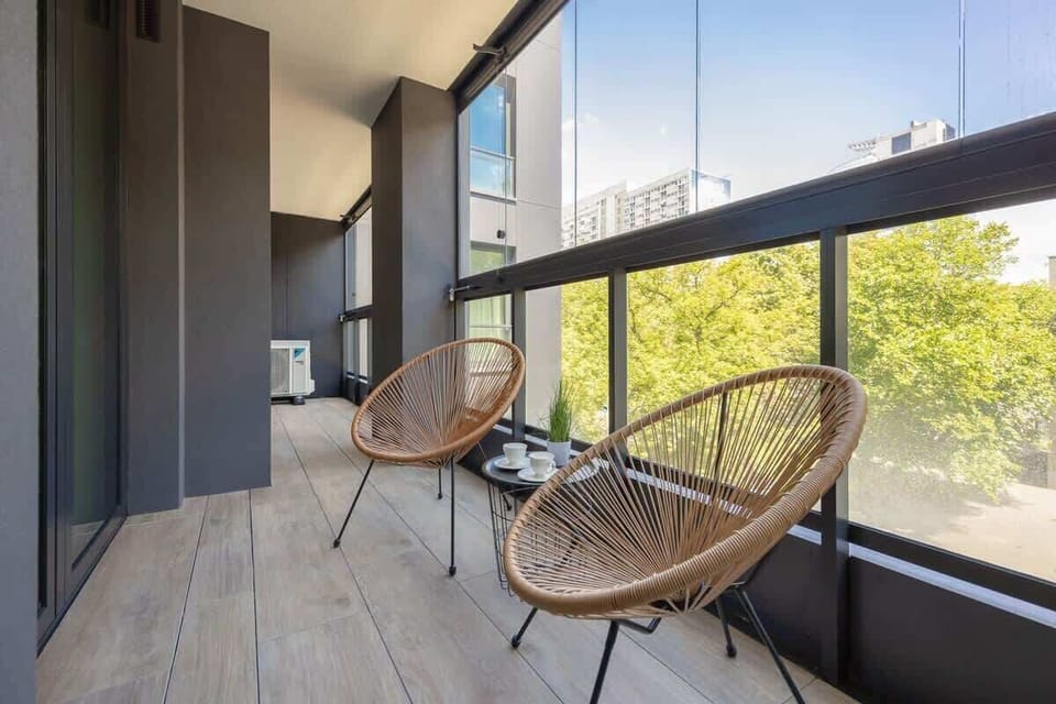 Balcony with garden furniture, creating a place to relax. The entire area is sheltered by a functional glass enclosure, which protects it from adverse weather conditions.