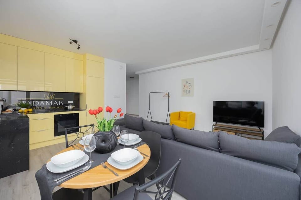A dining and living area with neutral tones and a round dining table set for two.