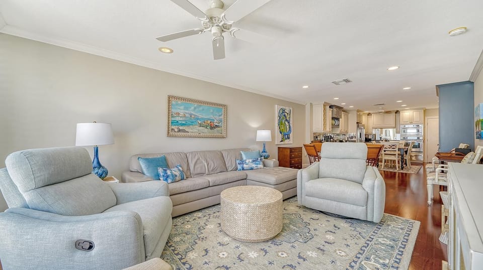 Two light blue recliners flank a taupe leather sectional on a patterned rug beneath a ceiling fan in the living room.