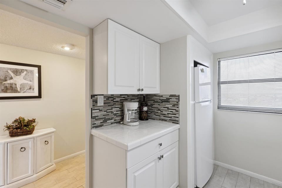 Modern coffee nook with sleek backsplash and cabinetry.