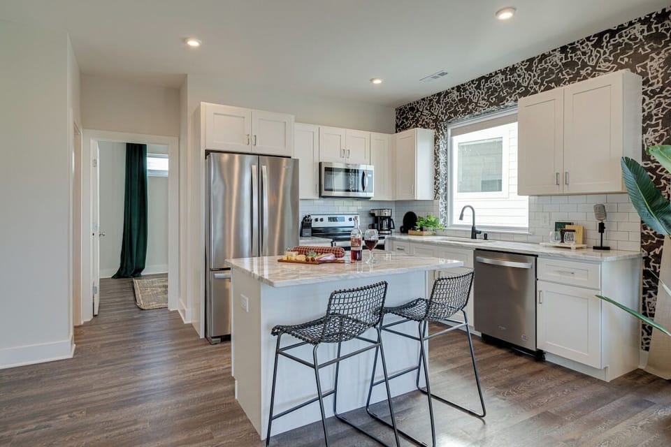 Open kitchen with stainless steel appliances, large island, breakfast bar seating, and is fully equipped with your basic cooking essentials.