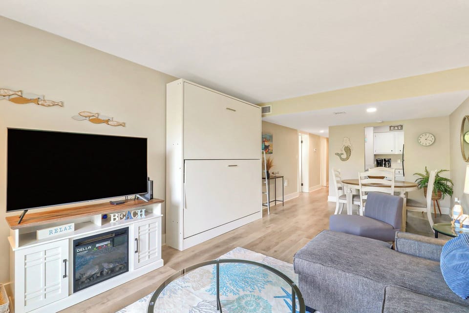 Cool coastal tones and honeyed wood floors create an airy, open layout perfect for slow mornings. Soft seating and a sleek fireplace invite you to settle in after a day by the water.