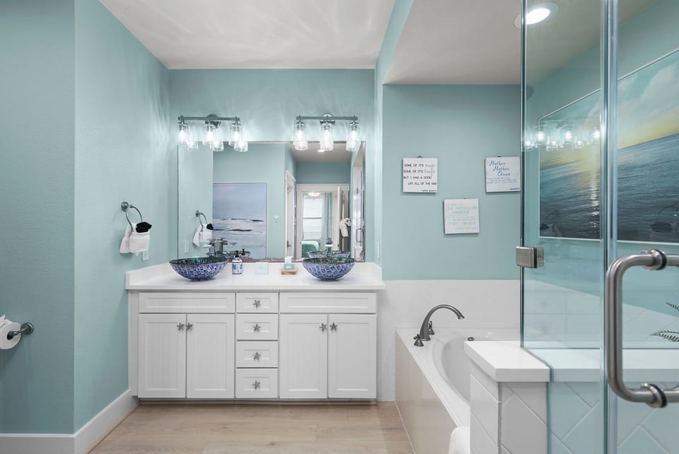Master bathroom with double sinks, walk-in shower, and soak tub