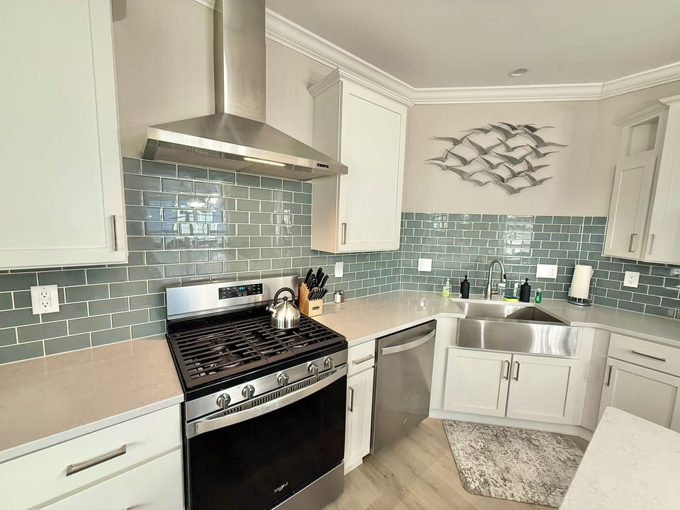 Sleek, fully stocked kitchen featuring a gas range, farmhouse sink, and beautiful tile backsplash—designed for both convenience and a high-end feel.